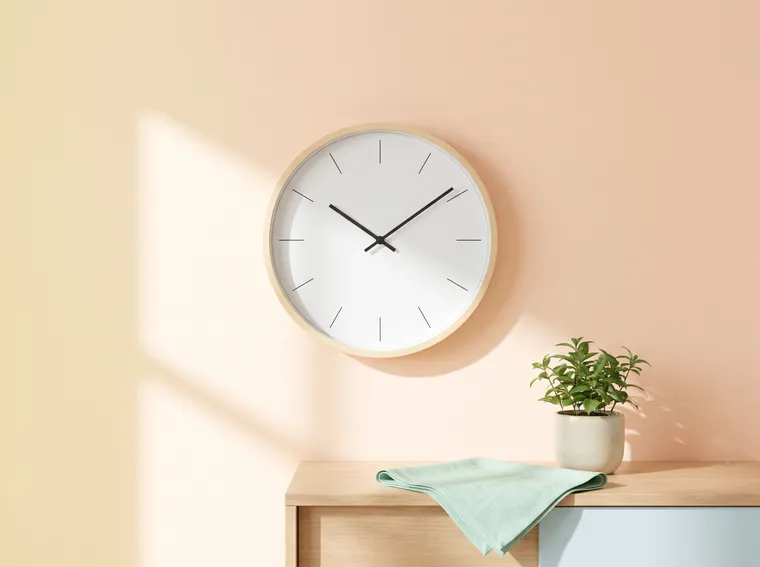 Illustration: a round wall clock without numerals, showing just after ten, on a peach wall in morning sunlight.